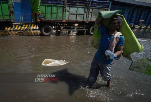 Pekerja melakukan masih melakukan proses bongkar muat saat terjadinya banjir rob atau banjir di tepi pantai karena permukaan air laut yang lebih tinggi daripada bibir pantai atau daratan di pesisir pantai Pelabuhan Kalimas, Surabaya, Jawa Timur, Rabu (18/5). Sebagian dermaga kawasan Pelabuhan Kalimas tergenang banjir rob akibat pasang air laut yang tinggi, namun aktifitas bongkar muat di lokasi tersebut masih berjalan normal. Foto: Julian Romadhon