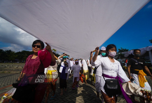 Umat Hindu mengikuti Upacara Melasti dengan membentangkan kain putih berjalan menuju pesisir laut Kenjeran, Surabaya, Jawa Timur, Minggu (19/3/2023). Upacara Melasti bertujuan menyucikan diri dan alam tersebut dilakukan untuk menyambut Hari Raya Nyepi Tahun Baru Saka 1945 yang jatuh pada Rabu (22/3). (foto: Julian Romadhon)