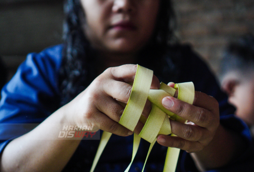 Sumiati (37) belajar membuat cangkang ketupat di jalan Tubanan Indah 1, Surabaya, Jawa Timur, Minggu (8/5/2021). Pembelajaran membuat cangkang ketupat tersebut diinisiasi oleh Trip for Education (TFE) dan Kampoeng Dolanan (KD) dengan tujuan anak-anak dan warga dikawasan tersebut mampu menganyam sendiri janur menjadi cangkang ketupat sehingga tradisi membuat ketupat untuk Lebaran Ketupat tetap lestari. Foto: Julian Romadhon
