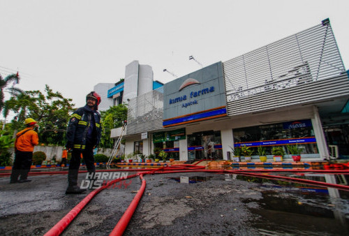 Petugas Dinas Pemadam Kebakaran melakukan proses pembasahan api yang melalap Apotik Kimia Farma di Jalan Diponegoro, Surabaya, Jawa Timur, Rabu (5/4/2023). Dinas Pemadam Kebakaran Kota Surabaya mengerahkan sebanyak 18 kendaraan untuk melakukan Pemadaman dalam kebakaran tersebut. (foto: Moch Sahirol)
