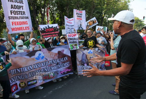 Sejumlah warga yang tergabung dalam komunitas pecinta hewan melakukan aksi serta memegang poster di 'Car Free Day' (CFD) di Taman Bungkul, Jalan Darmo, Surabaya, Jawa Timur, Minggu 7 Agustus 2022. Mereka dalam aksinya menyampaikan seruan untuk menghentikan konsumsi daging anjing dan kucing.