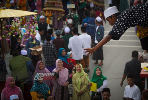 Warga berebut uang yang di bagikan saat acara Peringatan Maulid Nabi Muhammad di Kenjeran Surabaya, Jawa Timur, Jumat (7/10/2022). Peringatan Maulid Nabi Muhammad dilakukan dengan mengumpulkan sedekah berupa makanan, perabotan, dan pakaian dari warga setempat kemudian dibagikan kepada warga yang tidak mampu untuk memperingati dan mencontoh Nabi Muhammad. 
