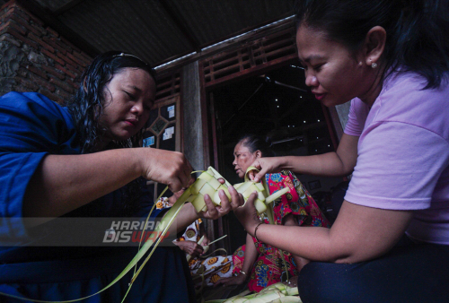 Sumiati 37 (kiri) dan Ratna Maira 35 (kanan) belajar membuat cangkang ketupat di jalan Tubanan Indah 1, Surabaya, Jawa Timur, Minggu (8/5/2021). Pembelajaran membuat cangkang ketupat tersebut diinisiasi oleh Trip for Education (TFE) dan Kampoeng Dolanan (KD) dengan tujuan anak-anak dan warga dikawasan tersebut mampu menganyam sendiri janur menjadi cangkang ketupat sehingga tradisi membuat ketupat untuk Lebaran Ketupat tetap lestari. Foto: Julian Romadhon