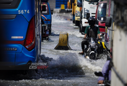 Pengendara kendaraan bermotor menerjang genangan air banjir rob di Jalan Kalimas Baru, Surabaya, Jawa Timur, Rabu (18/5). Pasang air laut yang tinggi akibat banjir rob menyebabkan sebagian akses jalan menuju Pelabuhan Kalimas dan penyeberangan Ujung terendam genangan air banjir rob. Foto: Julian Romadhon