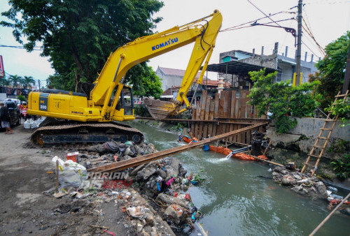 Pekerja mengoperasikan alat berat Excavator saat melakukan proses perbaikan tangkis sungai yang amblas di Simo Mulyo, Surabaya, Jawa Timur, Kamis (3/4/2023). Amblesnya tangkis sungai di kawasan tersebut disebabkan banjir yang terjadi Selasa (11/4/2023) dan Rabu (12/4/2023). (foto: Julian Romadhon)
