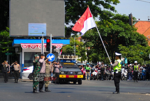 Petugas polisi dan TNI melakukan penghormatan bendera Merah Putih dalam rangka HUT Kemerdekaan RI memperingati detik - detik pembacaan Proklamasi di Simpang Empat Polisi Istimewa, Surabaya, Jawa Timur, Kamis, 17 Agustus 2023. Kegiatan menghentikan sejenak kendaraan bermotor dilokasi tersebut untuk mengambil sikap sempurna dalam rangka HUT Kemerdekaan RI memperingati detik - detik pembacaan Proklamasi. (Julian Romadhon/Harian Disway)