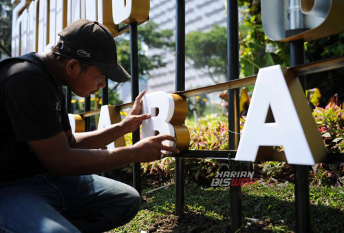 Pekerja melakukan proses pemasangan tulisan Aksara Jawa yang bertuliskan 