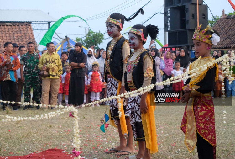 Pada prosesi peresmian, kepala desa hingga Forkopimka yang bersiap memotong untaian melati di pintu masuk tampak berjalan dengan cucuk lampah (pemandu jalan) yang dibawakan oleh anak-anak Desa Kraton sendiri. Mereka mengenakan pakaian penari, bahkan ada yang berkostum Punokawan. Sementara itu, Punokawan yang biasanya bersenjatakan sabit, bendo, dan kapak, dalam prosesi cucuk lampah ini mengganti senjata-senjata tersebut dengan mainan kitiran angin.
Foto: Boy Slamet/Harian Disway