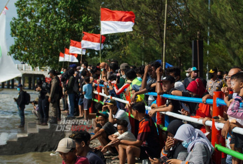 Warga beramai-ramai melihat peserta beradu kecepatan saat mengikuti lomba perahu layar di Pantai Kenjeran Surabaya, Jawa Timur, Sabtu 13 Agustus 2022. Lomba perahu layar tersebut diikuti sebanyak 37 perahu nelayan untuk memeriahkan peringatan HUT ke-77 Kemerdekaan RI. Foto: Miftakhul Rozaq