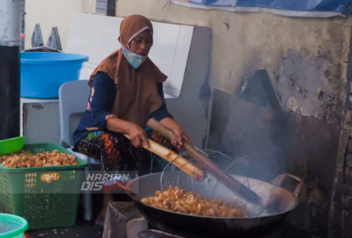 Salah satu pegawai di Toko Risma di Jalan Pantai Lama Kenjeran, Surabaya, Jawa Timur, Sabtu 30 April 2022 sedang menggoreng kerupuk khas Kenjeran yang sudah ditunggu pembeli. Foto: Safitri Riyanti