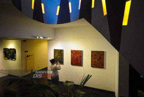 Pengunjung mendokumentasikan lukisan yang dipamerkan di Artspace, Artotel TS Suites, Surabaya, Jawa Timur, Jumat (7/7/2023). Pameran yang memajang sebanyak 23 karya lukis dari 4 pelaku seni rupa yang bergaya abstrak, Pop Art dan realis tersebut bertemakan Di Antara Hujan itu berlangsung hingga tanggal 7 Agustus 2023.