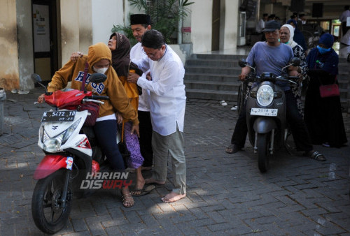 Pengurus masjid membatu warga fakir naik kendaraan bermotor saat berlangsungnya  pembagian Zakat Mal dan baksos bagi warga fakir di Masjid Baiturrozaq CitraLand, Surabaya, Jawa Timur, Minggu 13 Agustus 2023. Masjid Baiturrozaq CitraLand menyalurkan zakat untuk warga fakir sebanyak 200 penerima kategori fakir guna memenuhi kebutuhan sehari-hari. (Julian Romadhon/Harian Disway)