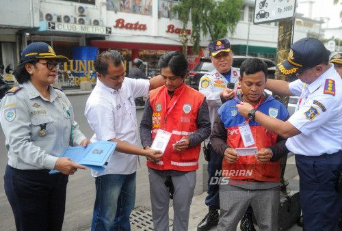 Petugas Dishub Kota Surabaya memberikan kalung kode Qris saat berlangsungnya penerapan parkir nontunai di Jalan Tunjungan Surabaya, Jawa TImur, Kamis, 1 Februari 2024. Pemkot Surabaya menerapkan pembayaran parkir nontunai yang bisa dilakukan dengan memindai kode QRIS yang telah disediakan. Sistem pembayaran parkir nontunai yang diterapkan ini dilakukan secara bertahap pada Februari 2024 di sejumlah lokasi parkir di Kota Surabaya. (Julian Romadhon/Harian Disway)