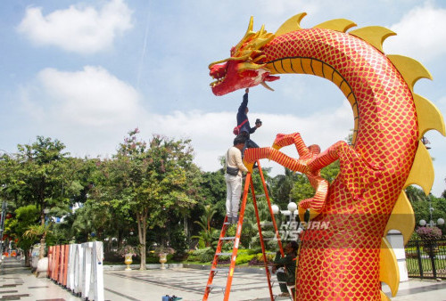 Pekerja tengah mendekorasi liong naga dalam menyambut perayaan Imlek di depan Taman Surya Balai Kota Surabaya, Jawa Timur, Kamis 1 Februari 2024. Ornamen naga kayu dengan panjang 20 meter dan tinggi 6 meter itu mempercantik Kota Surabaya dalam rangka menyambut perayaan Imlek tahun 2024. (Moch Sahirol/Harian Disway)