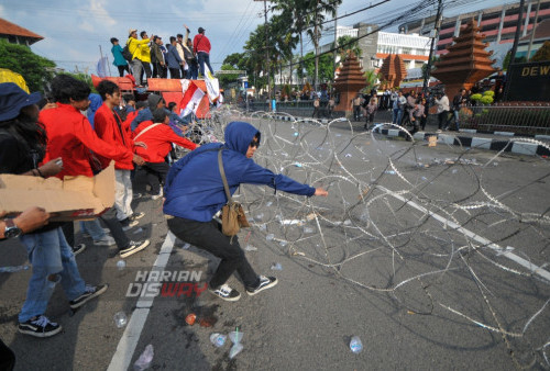 Mahasiswa menarik pagar barikade kawat duri siluet saat melakukan unjuk rasa mendesak pengesahan UU Perampasan Aset dan mencabut undang-undang Cipta Kerja di Gedung DPRD Jatim, Surabaya, Jawa Timur, Rabu (12/4/2023). Mahasiswa menuntut DPRD Jawa Timur untuk ikut menolak pengesahan Perppu Cipta Kerja Nomor 2 tahun 2022 yang dianggap tidak memihak kepentingan buruh dan pekerja di Indonesia. (foto: Julian Romadhon)