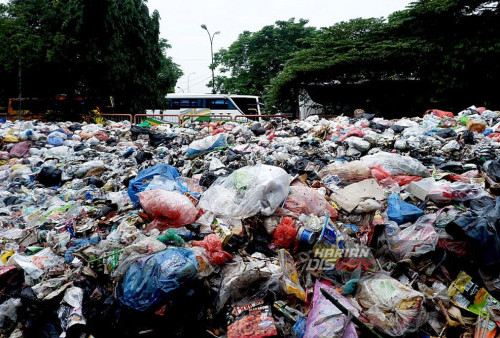 Kondisi tumpukan sampah yang menggunung hingga menghabiskan separuh jalan di parkir belakang bus Terminal Purabaya Bungurasih, Waru, Sidoarjo, Jawa Timur, Sabtu 24 Februari 2024. Tumpukan sampah yang semakin bertambah di Terminal Bus Bungurasih, Surabaya, telah mencemaskan pengguna transportasi umum dan menimbulkan kekhawatiran akan dampak lingkungan dan kesehatan. Para penumpang menyatakan keprihatinan mereka atas kondisi ini, dengan menyoroti aroma tidak sedap dan kemungkinan timbulnya penyakit. Pihak otoritas setempat didesak untuk segera mengambil langkah-langkah penyelamatan yang diperlukan untuk membersihkan area terminal dan meningkatkan pengelolaan limbah secara efektif. (M Azizi Yofiansyah/Harian Disway)