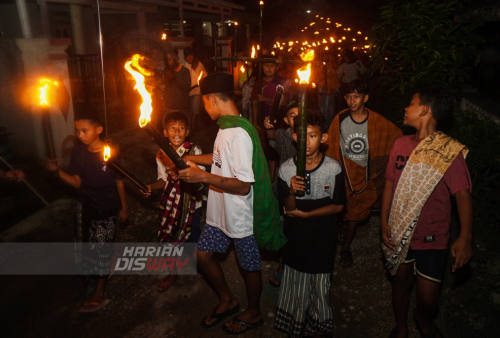 Sejumlah anak mengikuti takbir keliling dengan menggunakan oncor atau obor (sepotong bambu yang diisi minyak tanah, ujungnya disumpal dengan kain), di Lakarsantri, Surabaya, Jawa Timur, Minggu (1/5). Takbir keliling yang diikuti puluhan warga dengan berjalan kaki serta mobil pick up dari kampung ke kampung itu untuk menyambut malam hari raya Idul Fitri 1443 H. Foto: Julian Romadhon