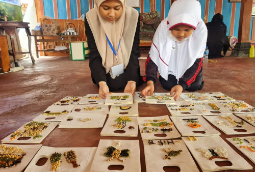 Rosa Puspa (kiri ) Mahasiswa KKN dari STIE Pemuda Surabaya (kiri ) memandu  Naila Putri untuk menata lukisan lukisan yang telah jadi. Rosa bersama rekan -rekan sesama Mahasiswa yang mengambil lokasi KKN di tempat itu memandu permainan permainan dengan memanfaatkan hasil panen kebun maupun pertanian untuk dijadikan karya seni. 