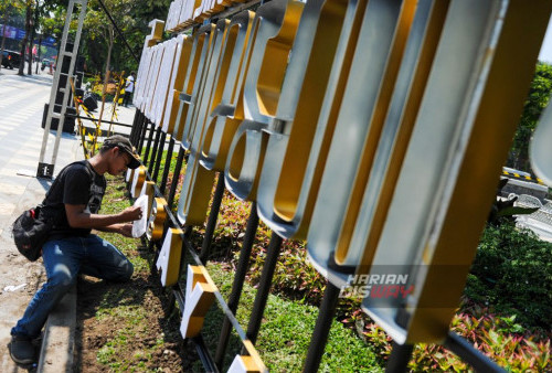 Pekerja melakukan proses pemasangan tulisan Aksara Jawa yang bertuliskan 